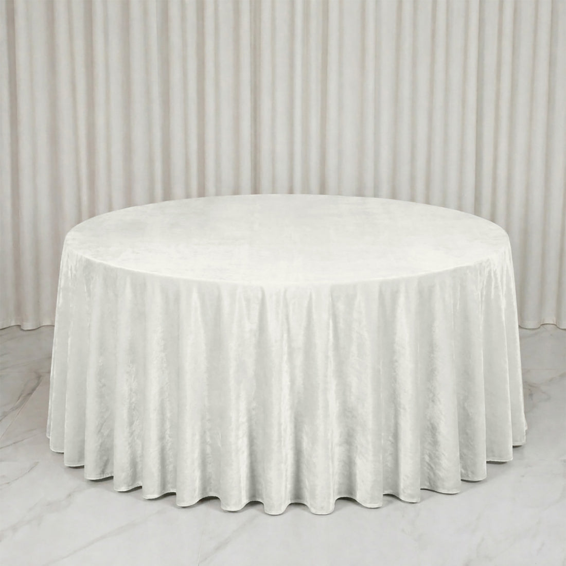 Round white tablecloth on a banquet table in a minimal white room