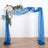 Blue draped wedding arch with floral accents on a plain background.