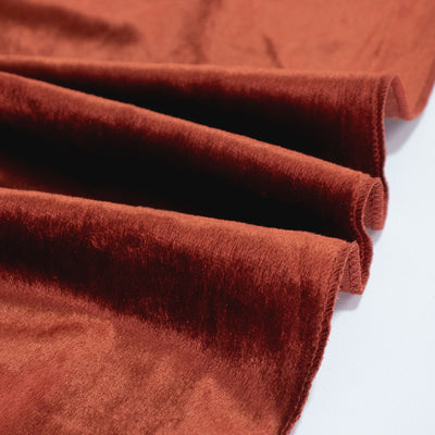 Rust velvet fabric rolls with soft plush texture close-up