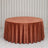 Rust velvet round table with draped tablecloth in elegant neutral room