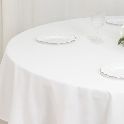 Elegant white table setting with scalloped plates and a glass.