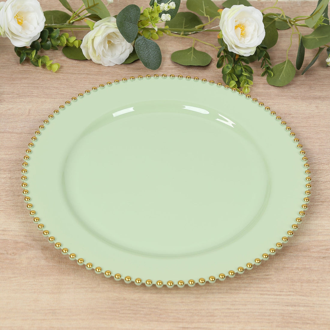 Mint green decorative plate with gold beaded rim on wooden surface.