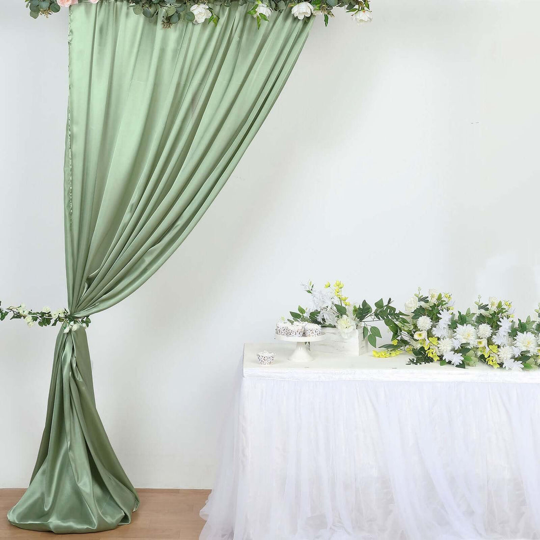 Green satin drapery with floral decor on a table in a softly lit setting.