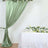 Green satin drapery with floral decor on a table in a softly lit setting.