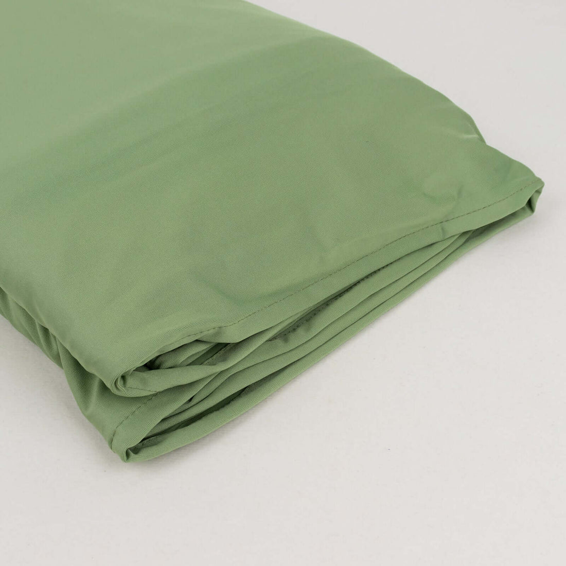 Folded green sleeping bag on a plain background.