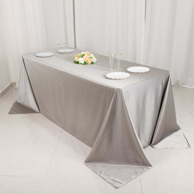 Elegant silver tablecloth draped over a table with floral centerpiece and plates.