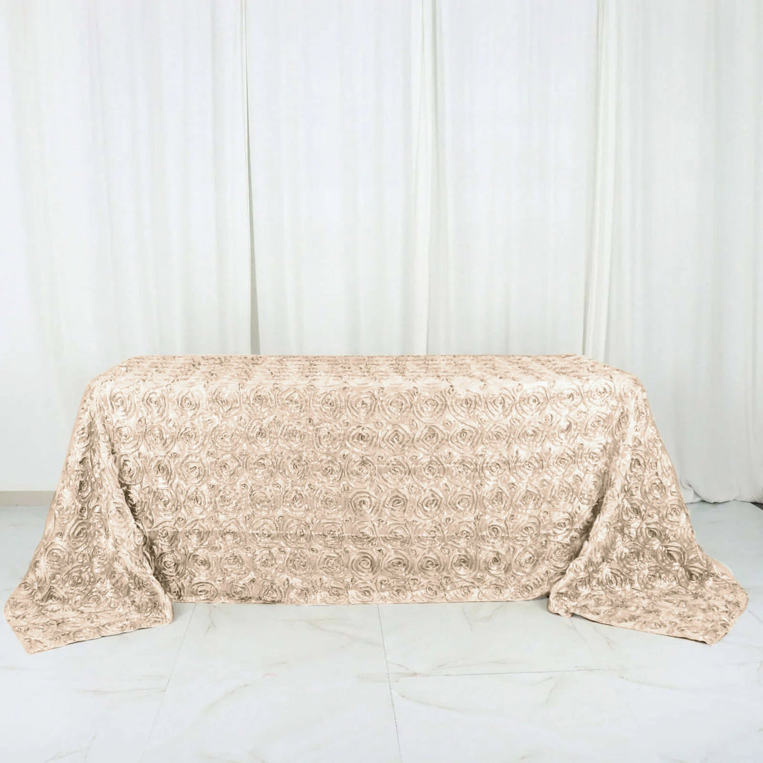 Rose textured table cover in champagne color on a plain backdrop.