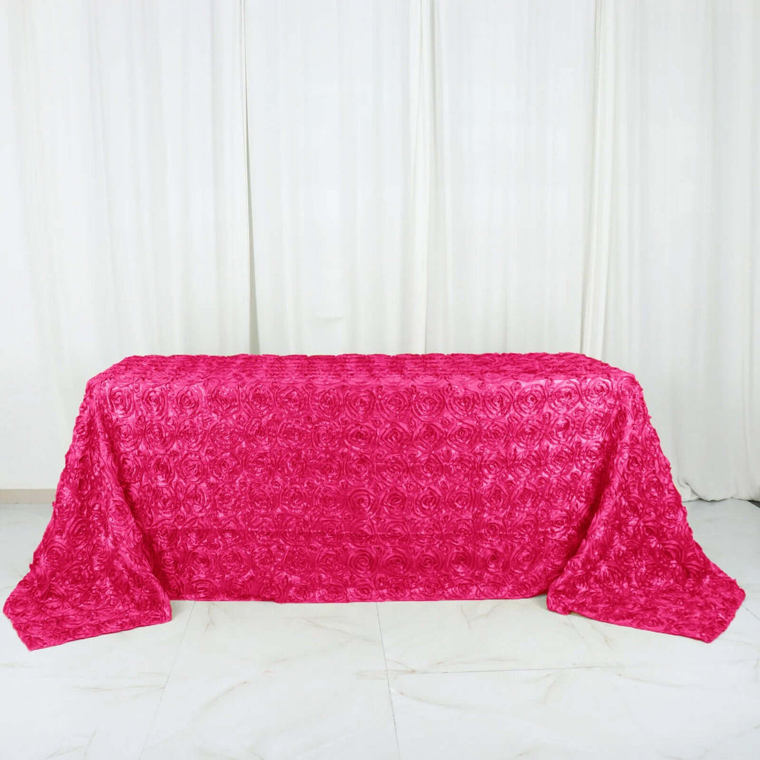Pink rose-patterned table cover on a plain backdrop.
