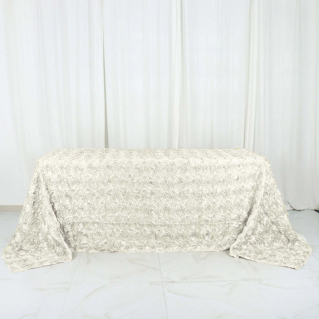 Textured rose-pattern tablecloth in soft cream color.