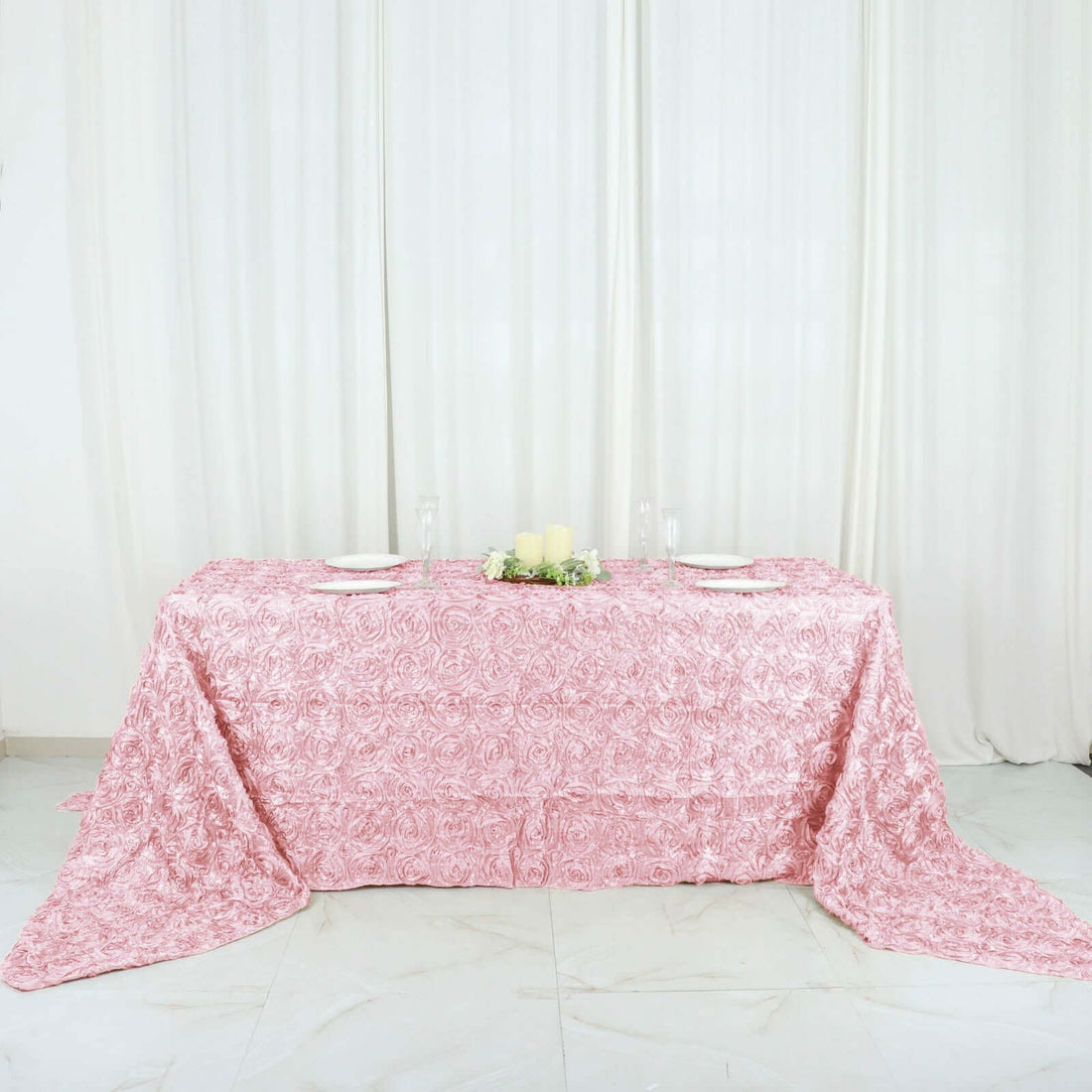Pink rose-patterned tablecloth draped over a table in a bright setting.