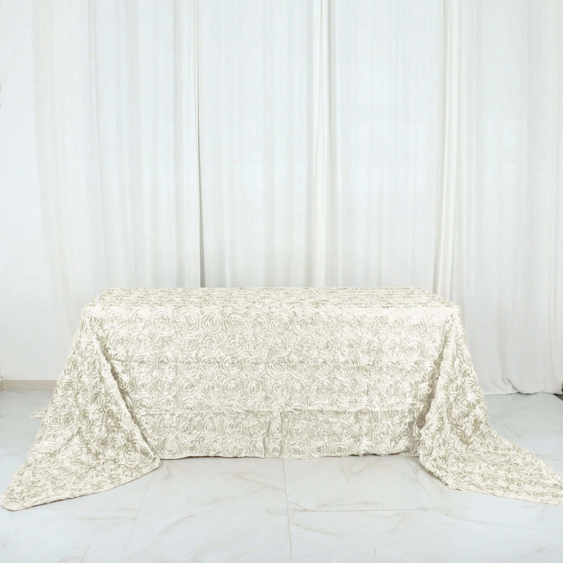 Textured cream tablecloth with floral design on a table.