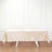 Beige satin tablecloth draped over a white table in a bright room.