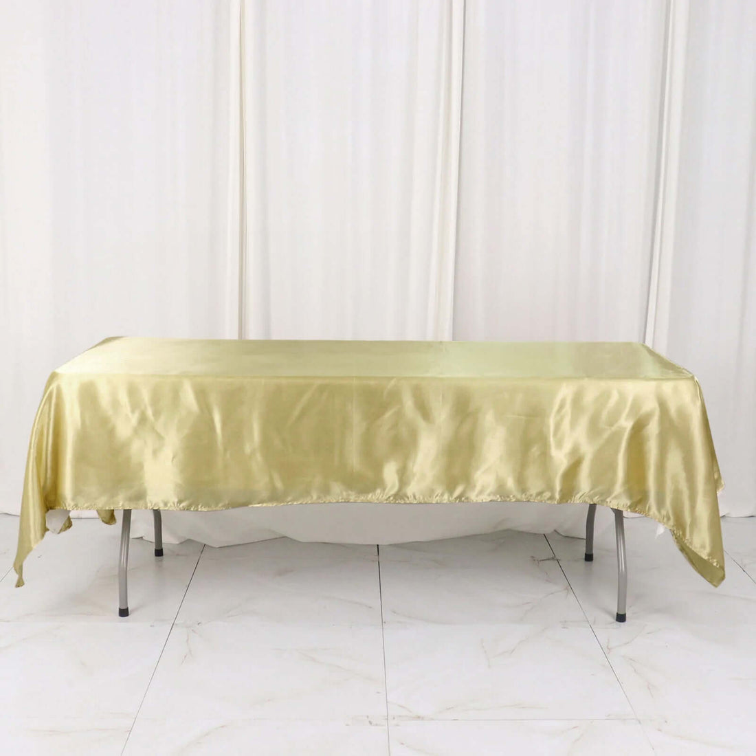 Gold satin tablecloth draped over a table against a plain backdrop