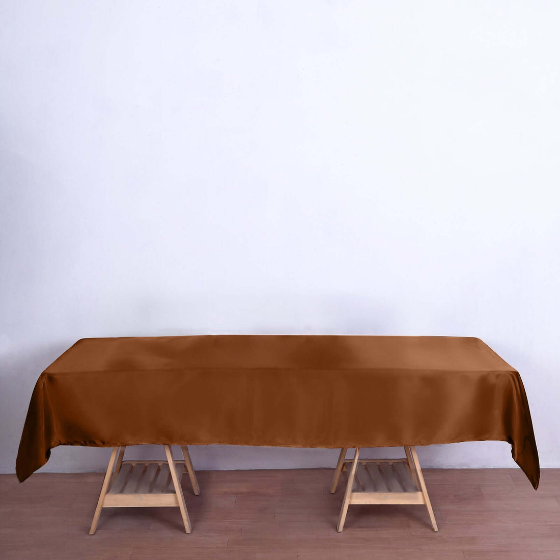 Brown tablecloth on wooden table against plain backdrop.