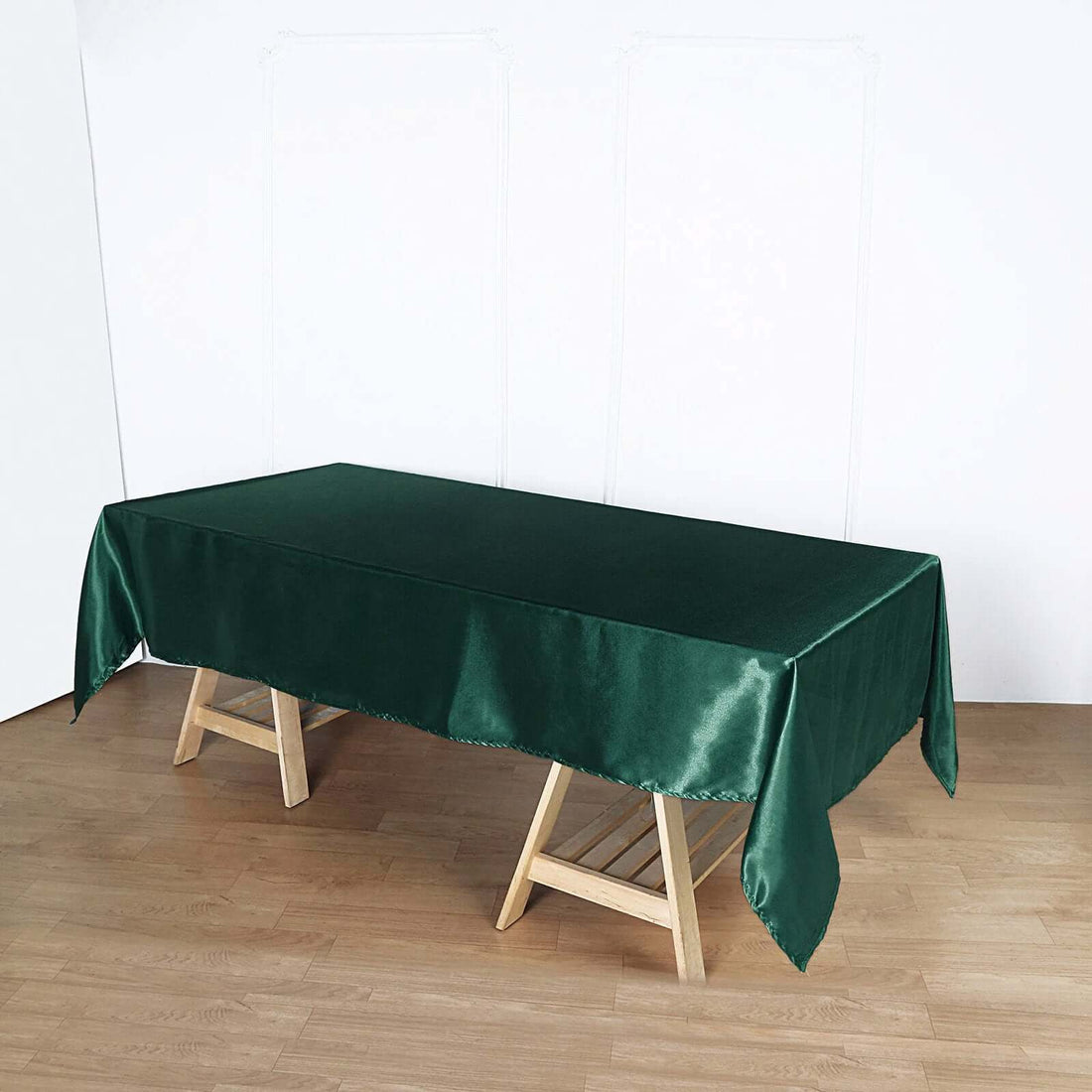 Green satin tablecloth on a wooden table in a studio setting.