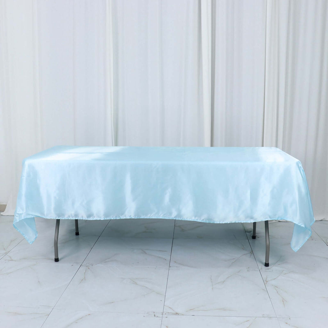 Light blue satin tablecloth draped over a table in a studio setting.
