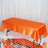 Orange satin tablecloth draped over a rectangular table.