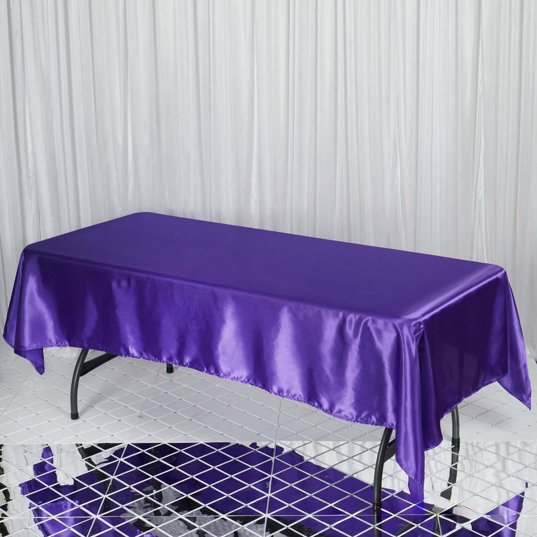 Purple satin tablecloth draped over a table in a studio setting.