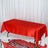 Red satin tablecloth on a table with a textured surface.