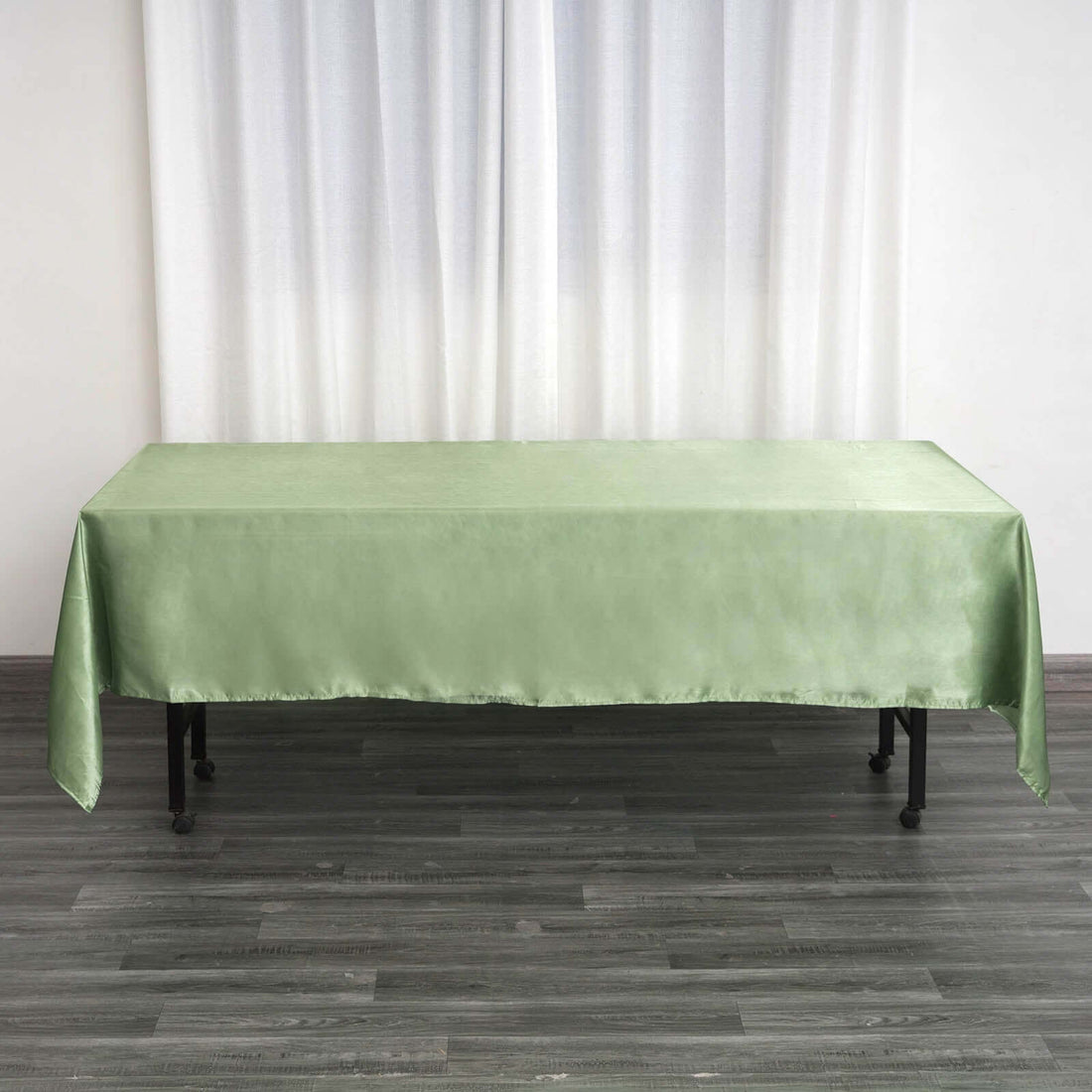 Green satin tablecloth draped over a table in a bright setting.