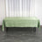 Green satin tablecloth draped over a table in a bright setting.