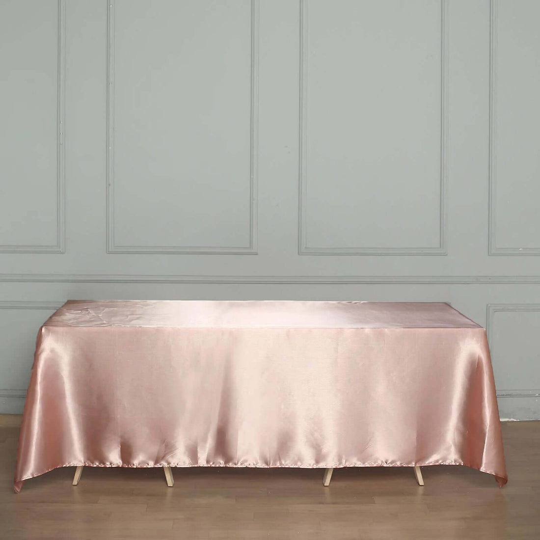 Satin pink tablecloth draped over a table in a minimalist setting.
