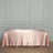 Satin pink tablecloth draped over a table in a minimalist setting.