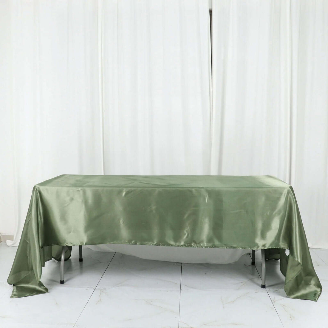 Green satin tablecloth draped over a table against a plain background.