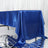 Blue satin tablecloth on a table against a draped backdrop.
