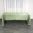 Green satin tablecloth on a wooden table with a white curtain backdrop.