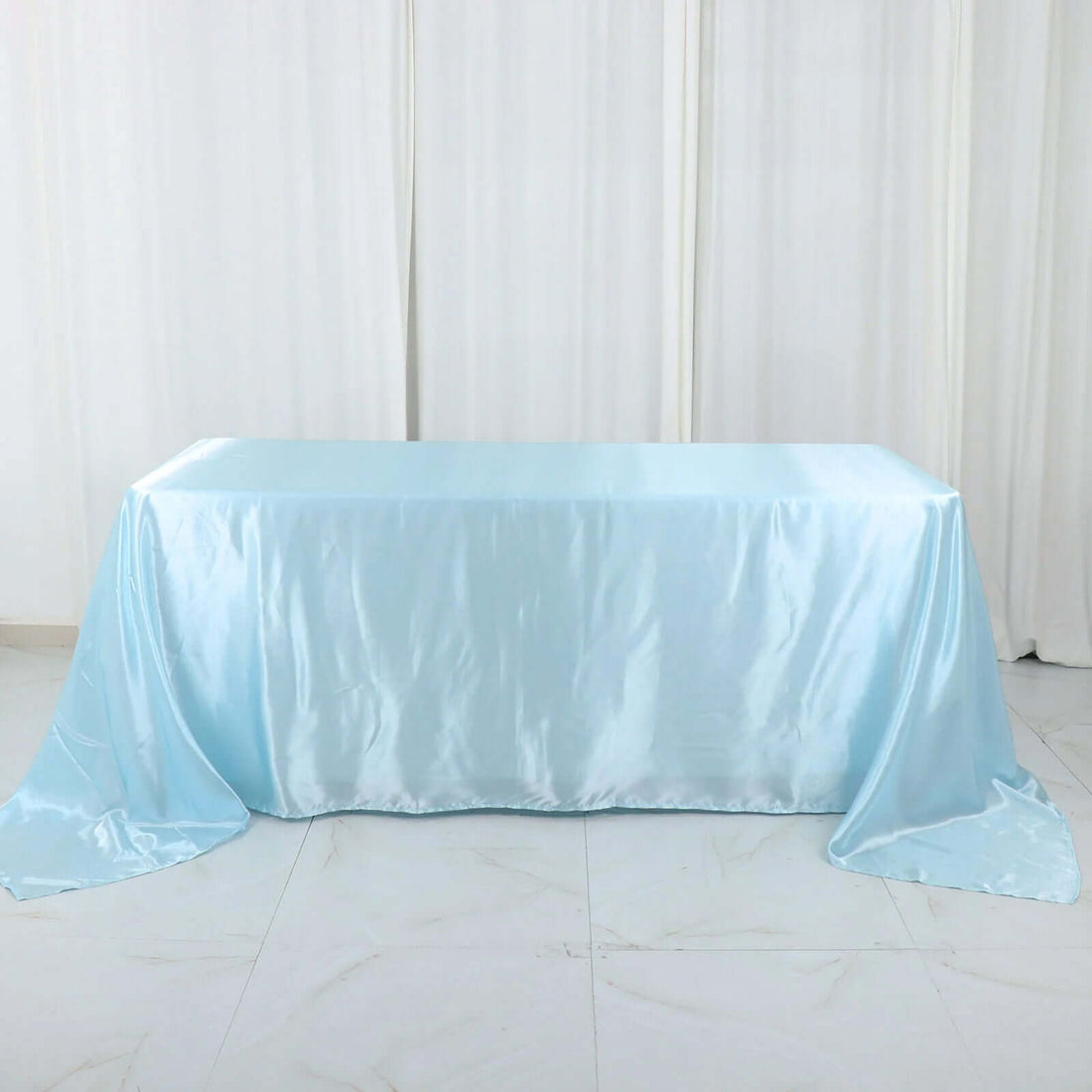 Light blue satin tablecloth draped over a table in a studio setting.