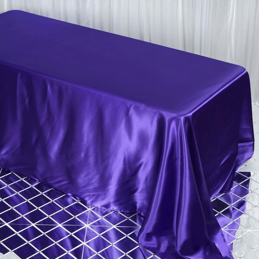 Purple satin tablecloth on a reflective surface.