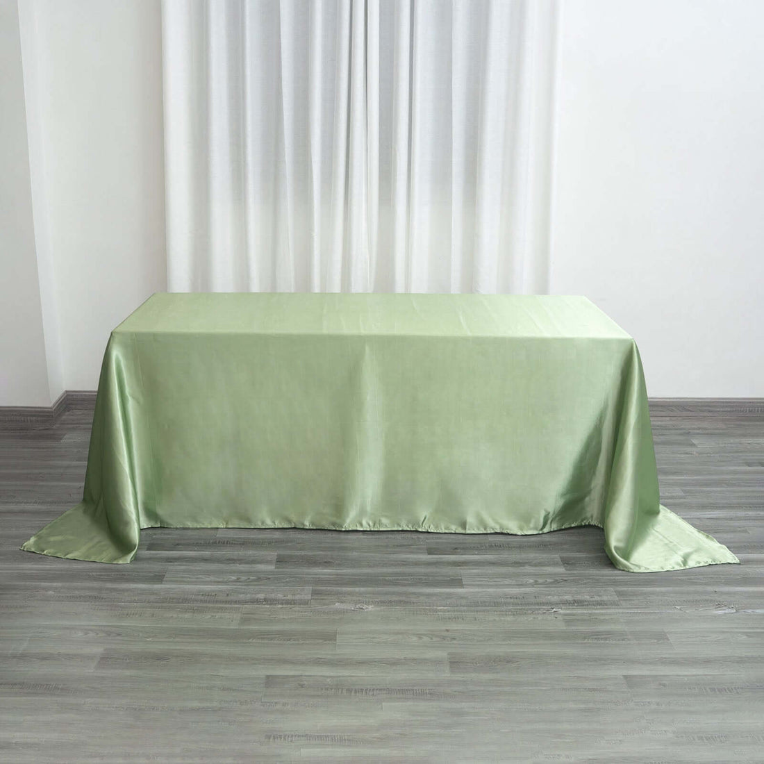 Green satin tablecloth draped over a table in a bright room.