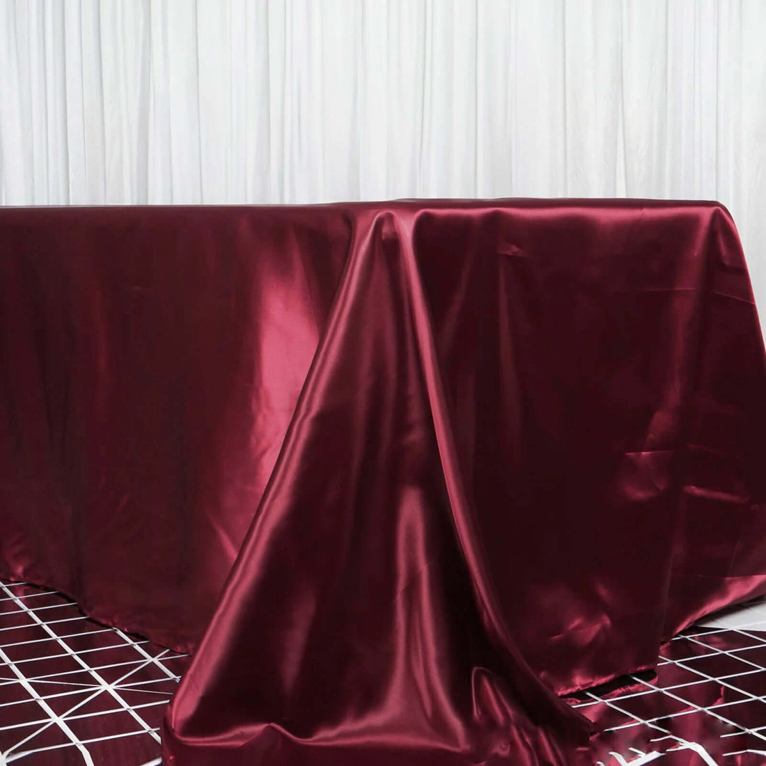 Burgundy satin tablecloth draped elegantly on a table.