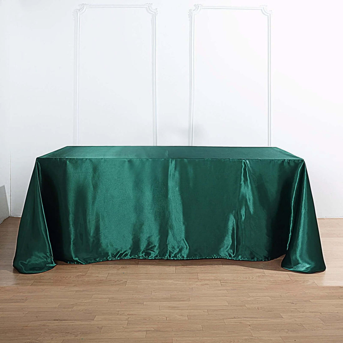 Green satin tablecloth on a wooden floor.