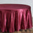 Burgundy round tablecloth on a wooden floor.