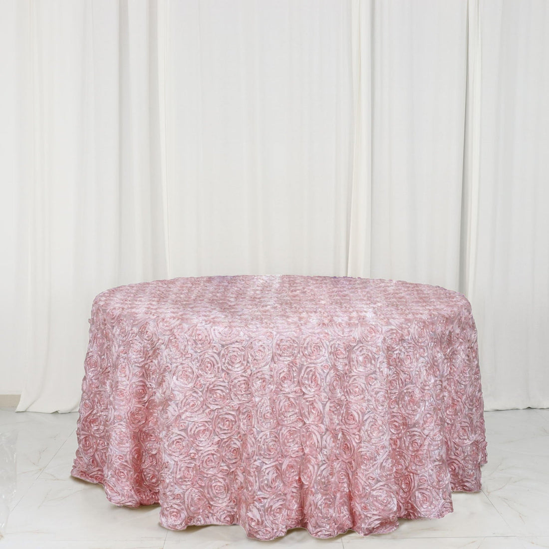 Pink rose-patterned tablecloth on a round table against a white backdrop.