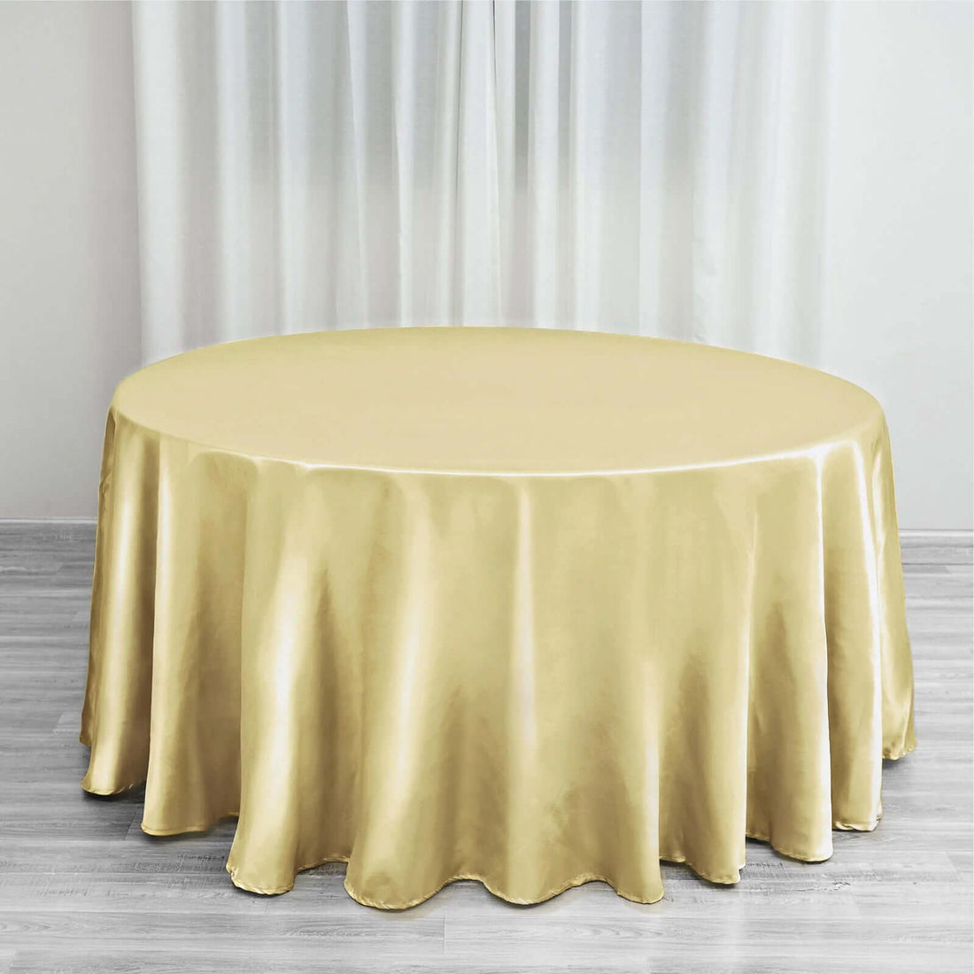 Gold tablecloth draped over a round table in a bright setting.