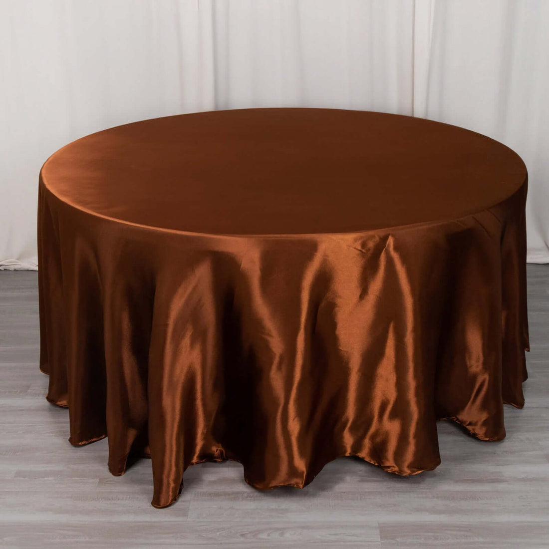 Round brown satin tablecloth on a plain surface.