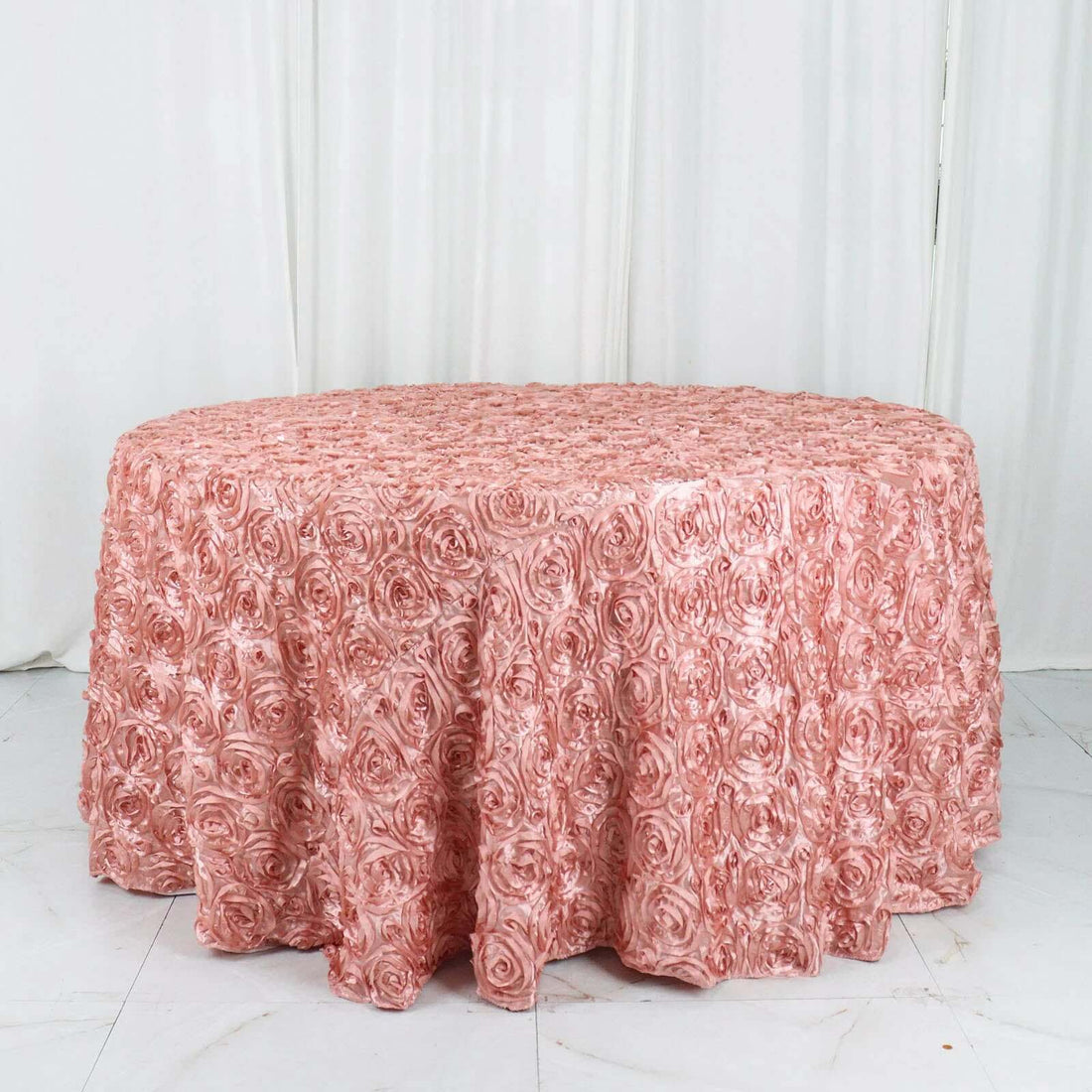 Pink rose-patterned round tablecloth on a plain white backdrop.