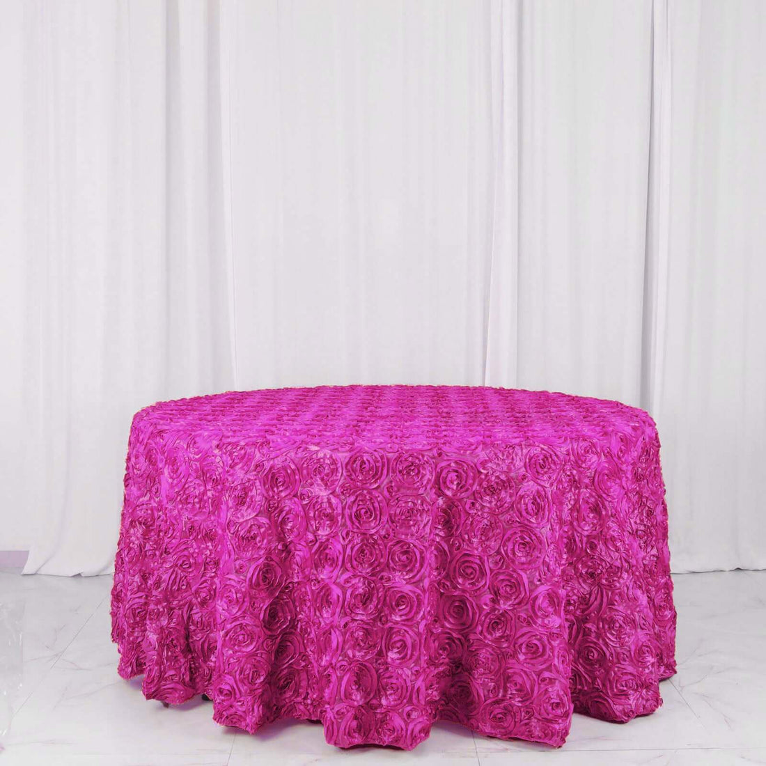 Pink rose-patterned tablecloth on a round table against a white backdrop.
