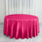 Round pink satin tablecloth on a wooden floor with curtains in the background.