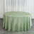 Round green satin tablecloth on a wooden floor with sheer curtains behind it.