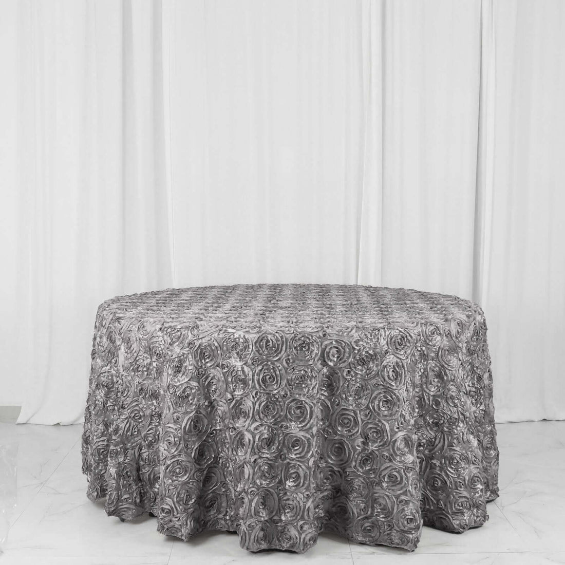 Gray floral tablecloth draped over a round table against a plain backdrop