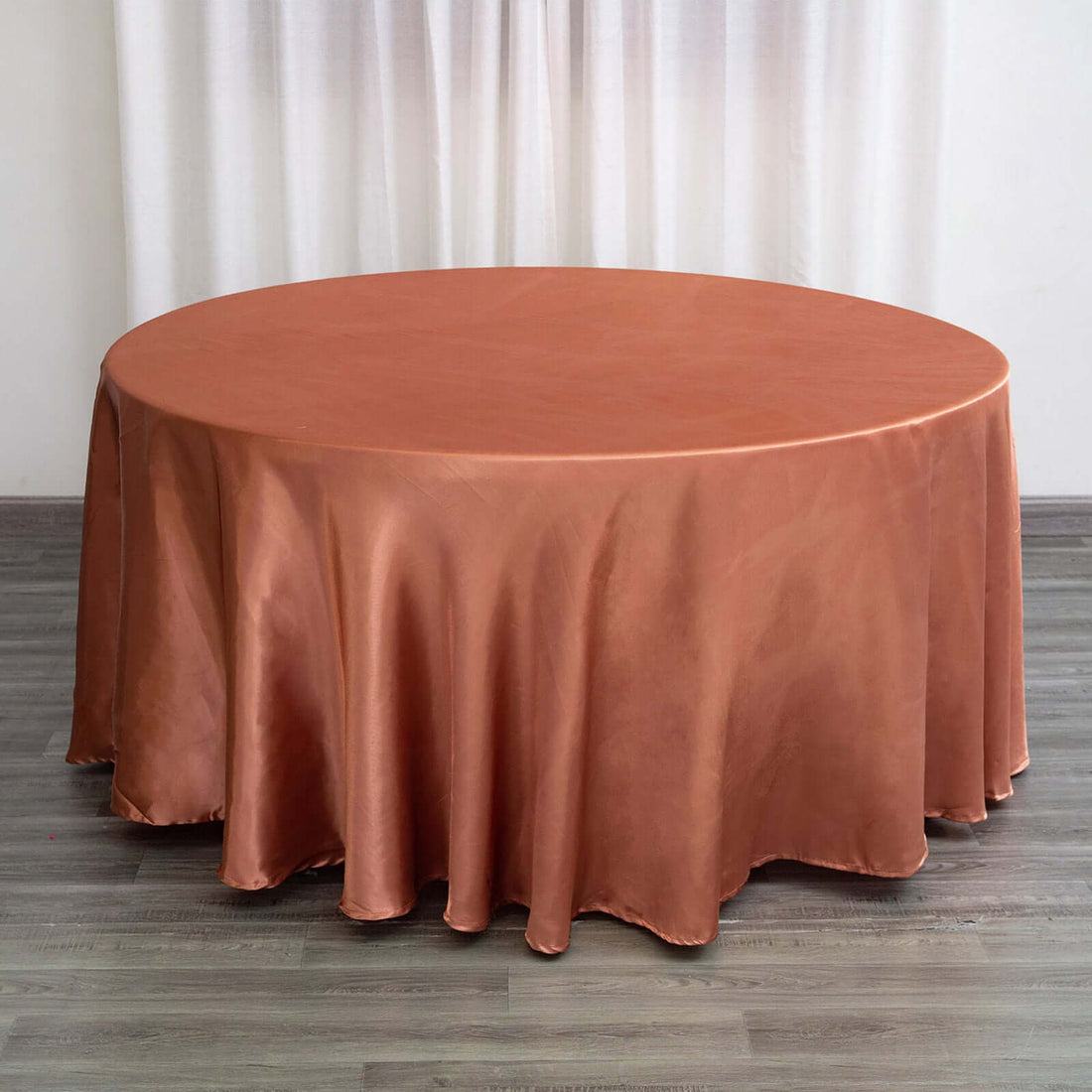 Round copper tablecloth draped on a circular table in a staged setting.