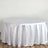 Round white tablecloth on a wooden floor.