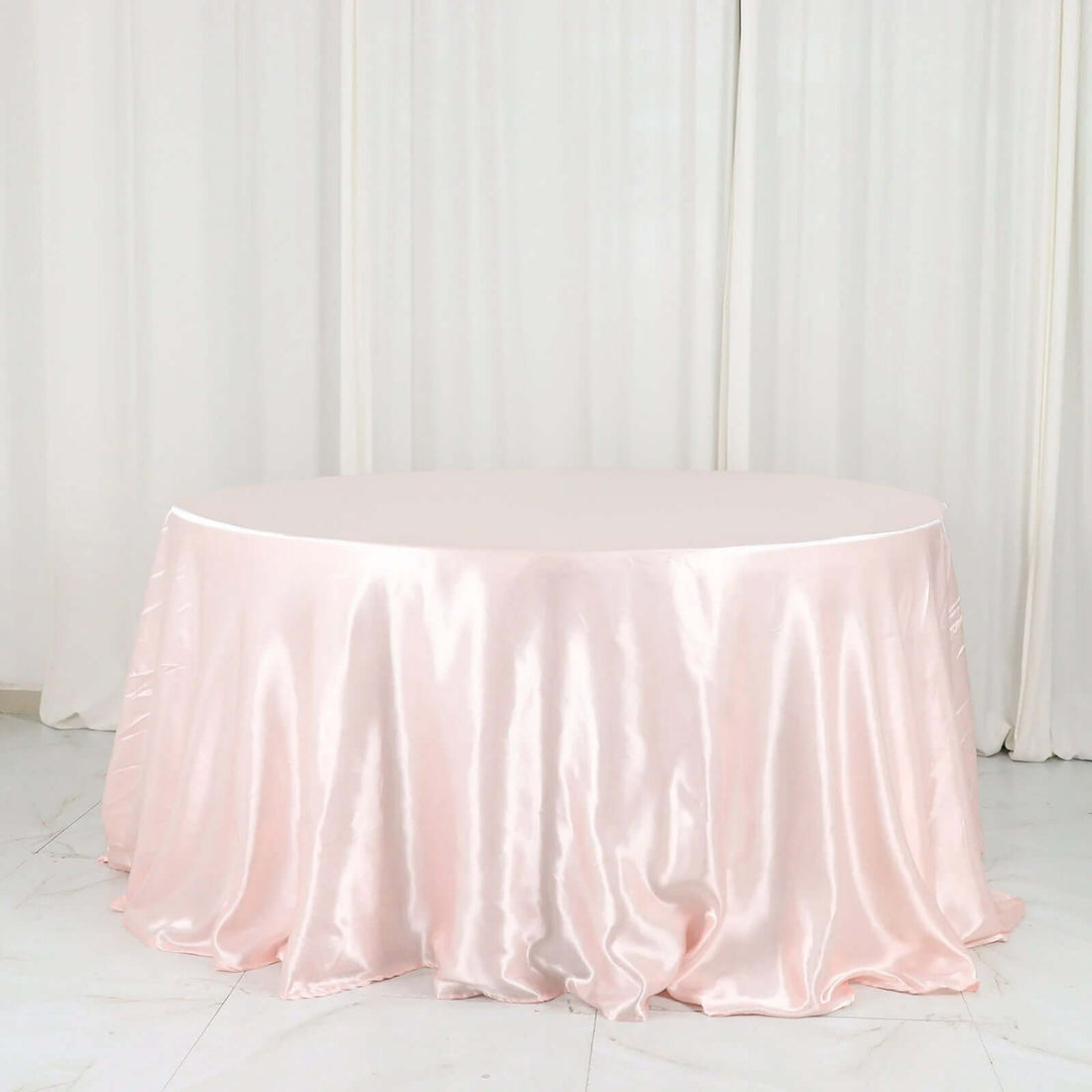 Round pink satin tablecloth on a plain backdrop.