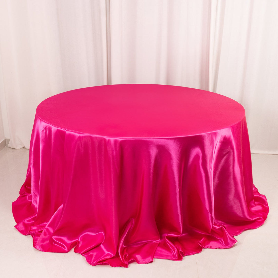 Round pink satin tablecloth with elegant draping.