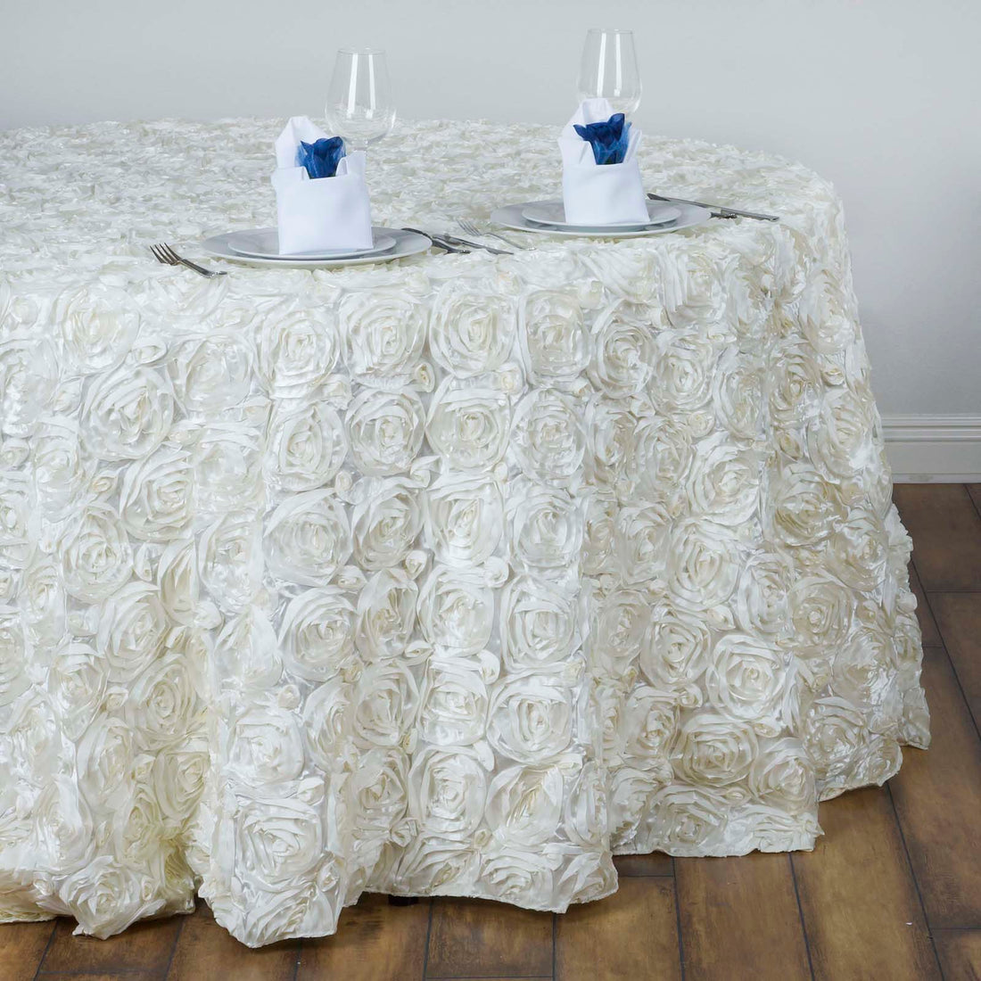 White rose tablecloth with elegant napkin and glassware setup.