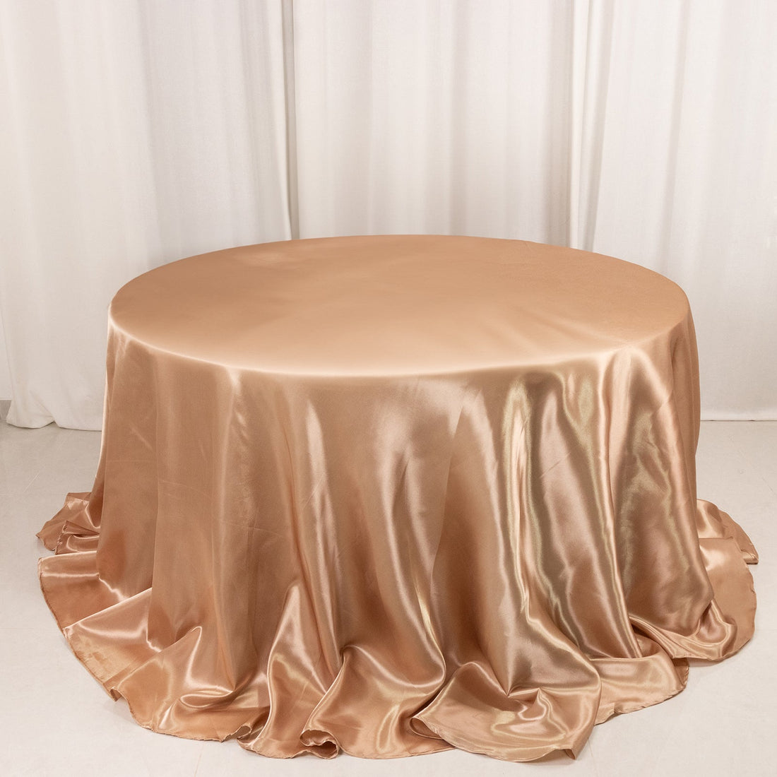 Round satin table cover in champagne color, elegantly draped.